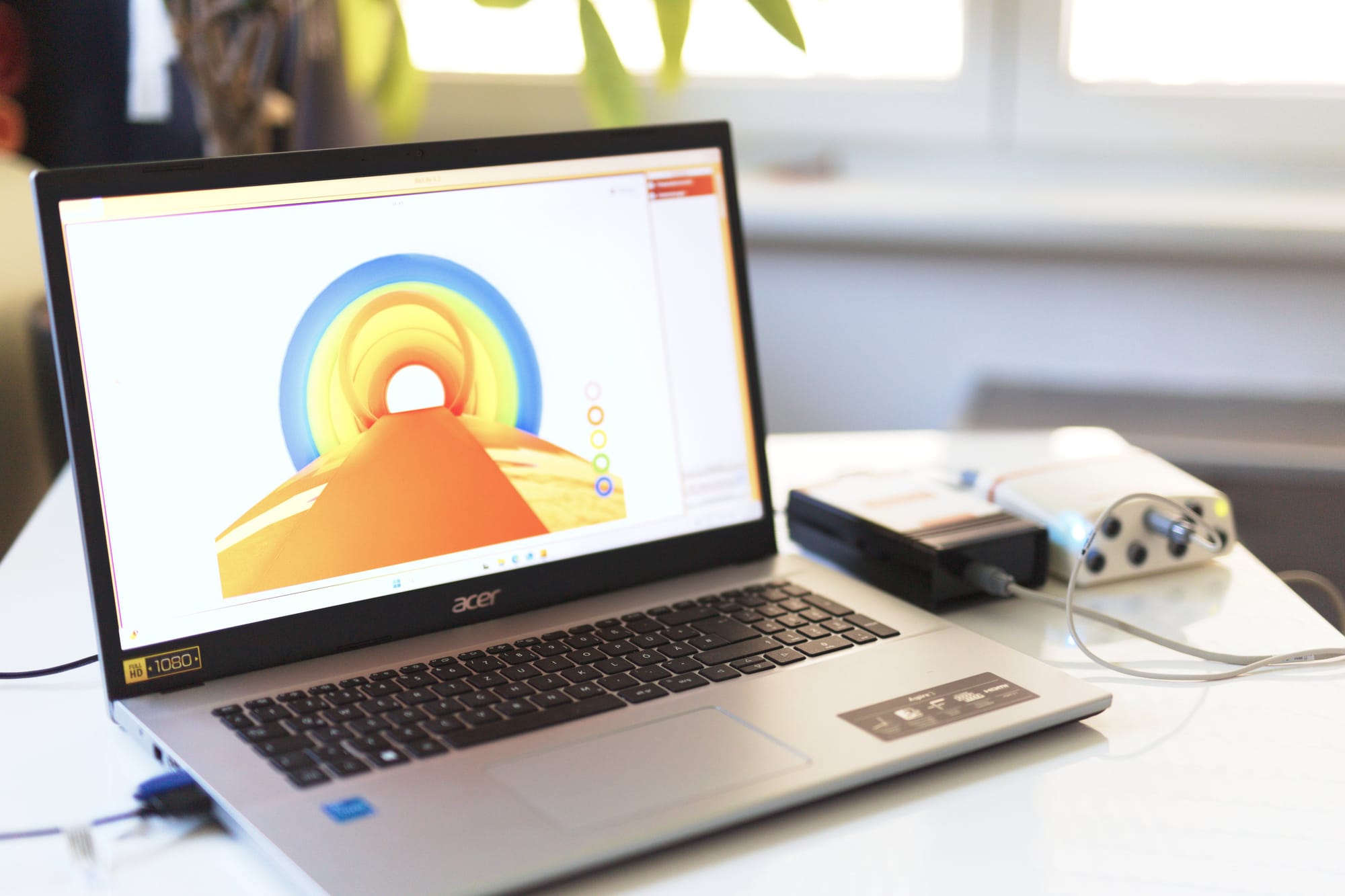Der "Regenbogenweg" wird am Laptop-Display angezeigt und das Biofeedback-Gerät liegt am Tisch